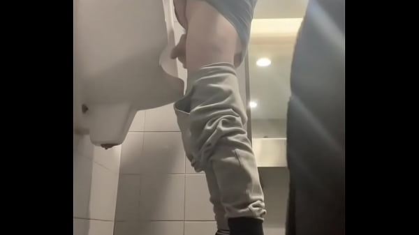 2 boys in sneakers having fun at public toilets’ urinal
